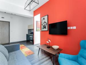 een woonkamer met een bank en een tv aan een rode muur bij Sanders Center Athens in Athene