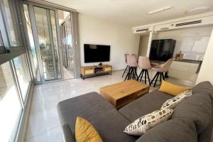 sala de estar con sofá y TV de pantalla plana en luxury boutique apartment 2BR With balcony on the sea, en Haifa