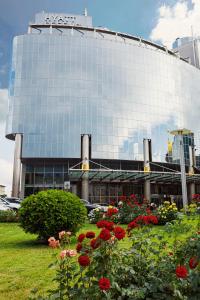 a large glass building with red flowers in front of it at Hyatt Regency Kyiv in Kyiv