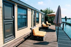 een terras met stoelen en een parasol op een huis bij Floatel - de Schans Alphen in Benedeneind