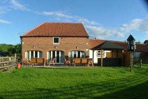 ein Backsteinhaus mit einem Tisch und Stühlen im Hof in der Unterkunft Manor Farm Holiday Cottages in Reighton