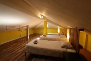 Duas camas num quarto com paredes amarelas e pisos em madeira em The Maverick Surfvillas na Lourinhã