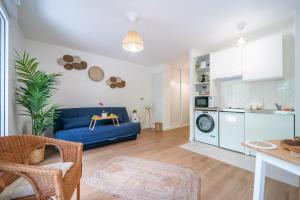a living room with a blue couch and a kitchen at Sensations - Studio dans le quartier daffaires in Rueil-Malmaison