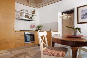 a kitchen with a wooden table and white chairs at Dimora Vittoria - Lago Maggiore in Casalzuigno +23 photos
