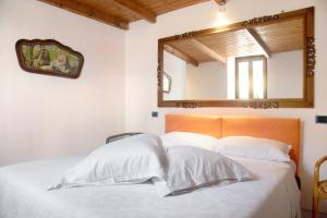 a bedroom with a bed with a mirror on the wall at Dimora Vittoria - Lago Maggiore in Casalzuigno