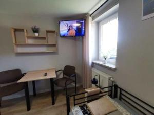 uma sala de estar com uma mesa e uma televisão na parede em Tanie Noclegi, kwatery, pokoje do wynajęcia , TARGI KIELCE em Kielce