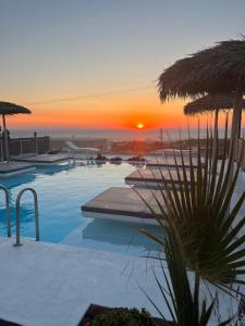 una piscina con puesta de sol en el fondo en Nalu Suites, en Fira