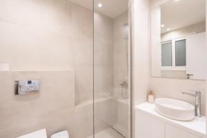 een witte badkamer met een wastafel en een douche bij Newly Renovated 2 Bedroom Apartment, 5min to metro in Athene