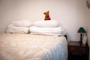 un orsacchiotto seduto sopra i cuscini su un letto di Santa's Row house a Rovaniemi