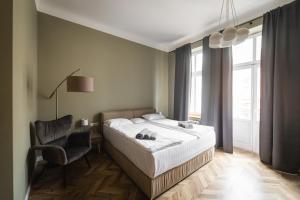 a bedroom with a bed and a chair and a window at Apartments JustLvivIt at the Rynok Square in Lviv