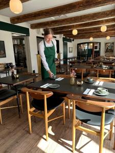 a woman standing in a dining room with tables at Hotel Steenbergs in Nykøbing Mors