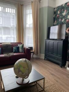 uma sala de estar com televisão e um globo sobre uma mesa em West London stunning garden flat - period features em Londres