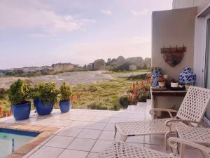 a patio with chairs and potted plants and a pool at The Boulders Langebaan in Langebaan