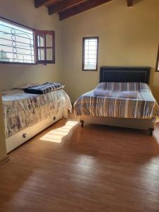 Departamento Mendoza في مايبو: سريرين في غرفة وأرضيات خشبية ونوافذ