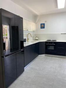 a large kitchen with black cabinets and a stove at Romi's suite by LOREN VILLAGE in Neve Zohar