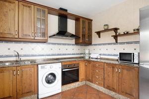 eine Küche mit Holzschränken, einer Waschmaschine und einem Trockner in der Unterkunft Villa Juani Sólo familias in Roche