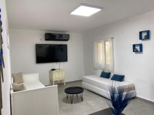 Habitación blanca con cama y TV en Romi's suite by LOREN VILLAGE, en Neve Zohar