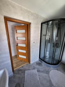 a bathroom with a large glass shower and a door at Witowiański Dworek in Witów