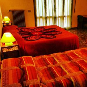 B&B Francesco في بيزا: غرفة نوم بسريرين ذات أغطية حمراء ومصباح