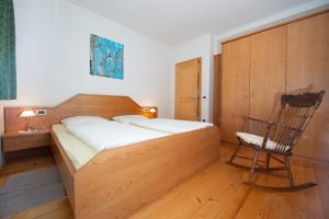 a bedroom with a wooden bed and a chair at Steidlerhof in Bolzano