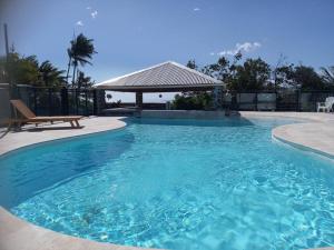 a large swimming pool with a bench and a gazebo at Maison mitoyenne F3 avec piscine partagée - Résidence Plaiz'Anse in Petite Île