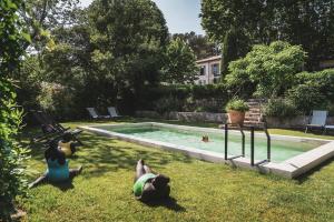 un grupo de personas yaciendo en la hierba junto a una piscina en Les Lodges Sainte-Victoire Hotel & Spa en Aix-en-Provence