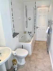 a white bathroom with a tub and a toilet and a sink at Perfect location for Racecourse and town centre in Cheltenham
