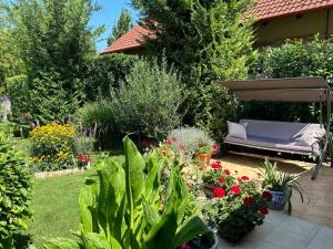 a garden with a bench and a bunch of flowers at CSAOL Apartman ház in Velence