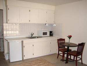 a kitchen with white cabinets and a table and a microwave at Swiss Motel in Riverhead