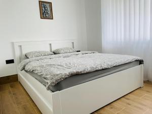 a white bed in a white bedroom with a white wall at Alto Turtas Apartamentai in Šiauliai