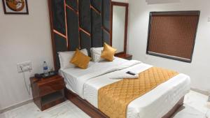 a bedroom with a large bed with yellow pillows at Hotel Palms Residency, Chembur Mumbai in Mumbai
