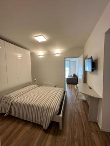 San Pellegrino Suites في سان بيليغرينو تيرمي: غرفة نوم بسرير ومكتب وتلفزيون