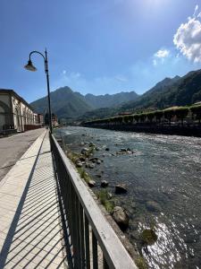 eine Brücke über einen Fluss mit Bergen im Hintergrund in der Unterkunft San Pellegrino Suites in San Pellegrino Terme