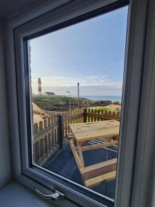 a window with a table and a view of the beach at Puffin Cottage in Boddam