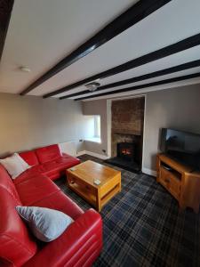 a living room with a red couch and a fireplace at Puffin Cottage in Boddam