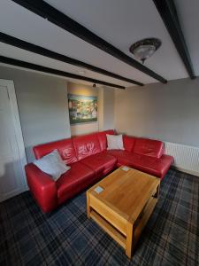 een woonkamer met een rode bank en een salontafel bij Puffin Cottage in Boddam