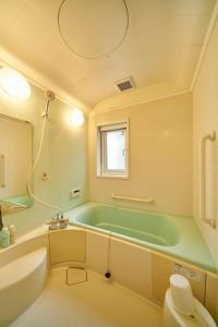 baño con bañera verde y ventana en Guest House Kingyo - Vacation STAY 14499, en Sapporo