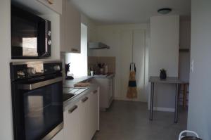 een keuken met witte kasten en een zwarte oven bij La maison de Michelle in Lugny