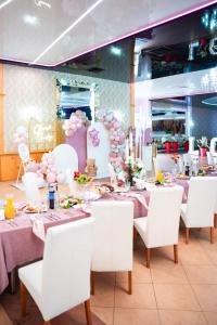 a dining room with tables and white chairs and pink decorations at Hotel U Grubego in Wielogóra