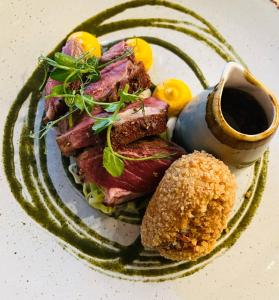 a plate of food with meat and a tablespoon of sauce at Sign of the Angel in Lacock