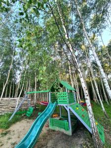 a playground with a slide in the woods at Domki Mierzeja in Drewnica
