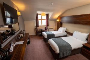 ein Hotelzimmer mit 2 Betten und einem Tisch in der Unterkunft The Fernhurst by Greene King Inns in Blackburn