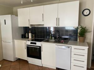Una cocina con gabinetes blancos y un fregadero. en WALO APARTMENTS Tromsø - Alfheim 10 min walk to city centre - No parking, en Tromsø