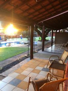 eine Terrasse mit Stühlen, einem Tisch und einem Pool in der Unterkunft Pousada Beco da Lua in Olímpia