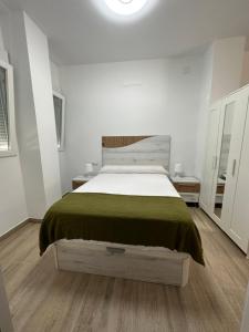 um quarto branco com uma cama com um cobertor verde em Sky Garden Málaga Centro em Málaga