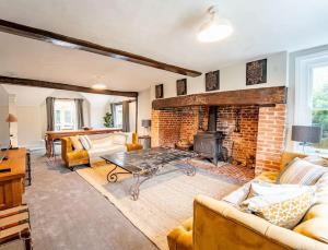 a living room with a fireplace and a brick wall at 5 Bed Farmhouse Suitable for Contractors Private Parking in Potter Street