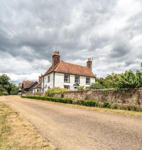 a white house sitting on the side of a road at Large 5-Bedroom Farmhouse Sleeps 10 with Parking and Wifi in Potter Street