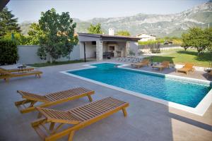 a swimming pool with benches and a house at Villa Village Mostar in Mostar