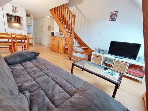 uma sala de estar com um sofá e uma televisão em Chez Charlotte, T3 duplex, vue montagne, parking gratuit, 4 personnes em Luchon