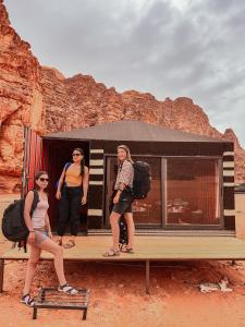 drie vrouwen op een houten platform voor een bus bij Desert Bird Camp in Wadi Rum